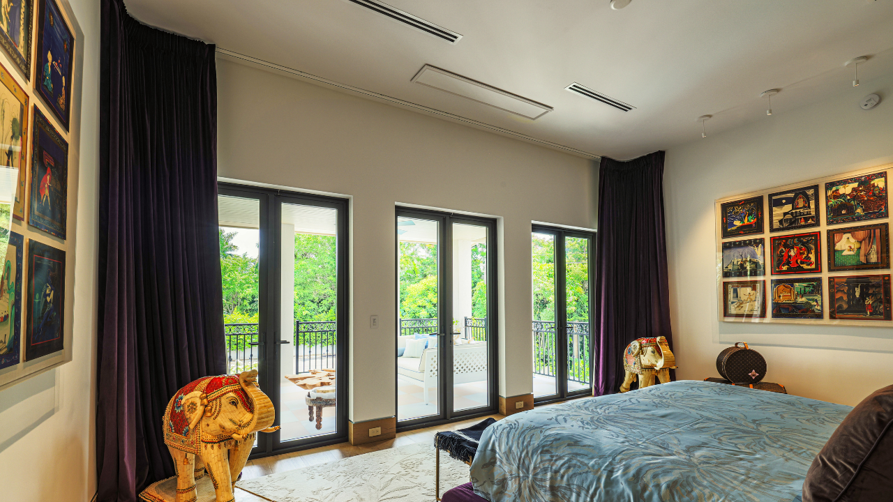 Looking across a bedroom out toward a covered balcony with two elephant statues flanking a bed.